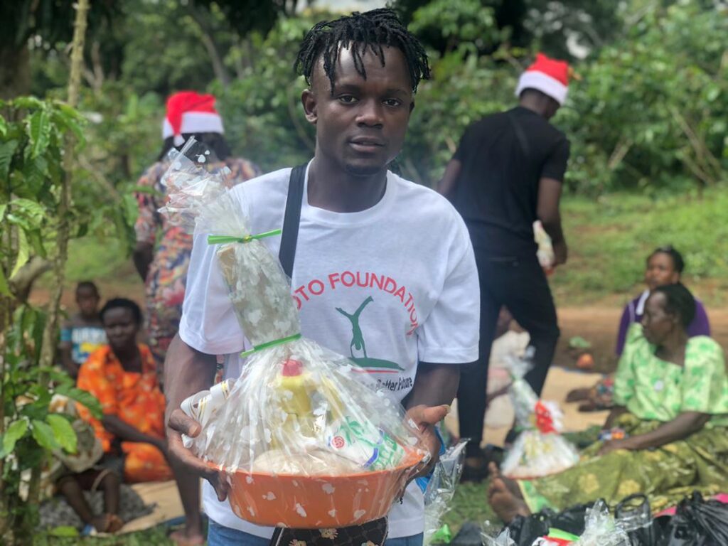 A teen holds a gift basin as villagers sit behind him, waiting to receive basins