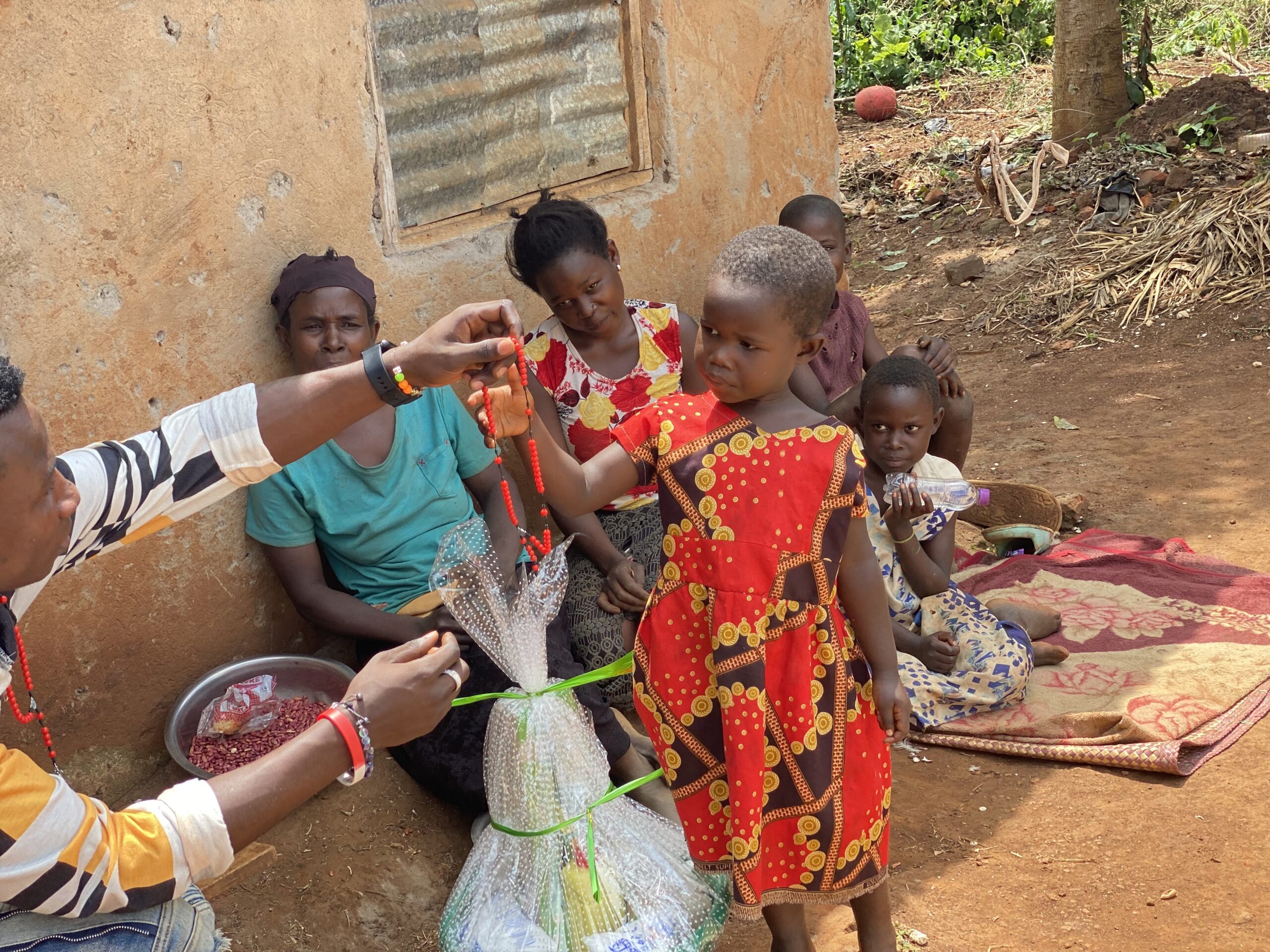 A small girl receives a rosary from a gift basin as her family looks on